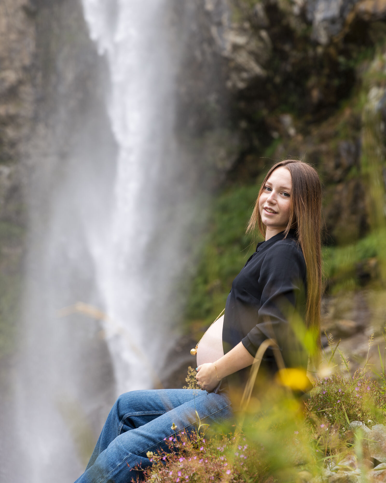 Lou-ann assise devant la cascade, les mains sur le ventre