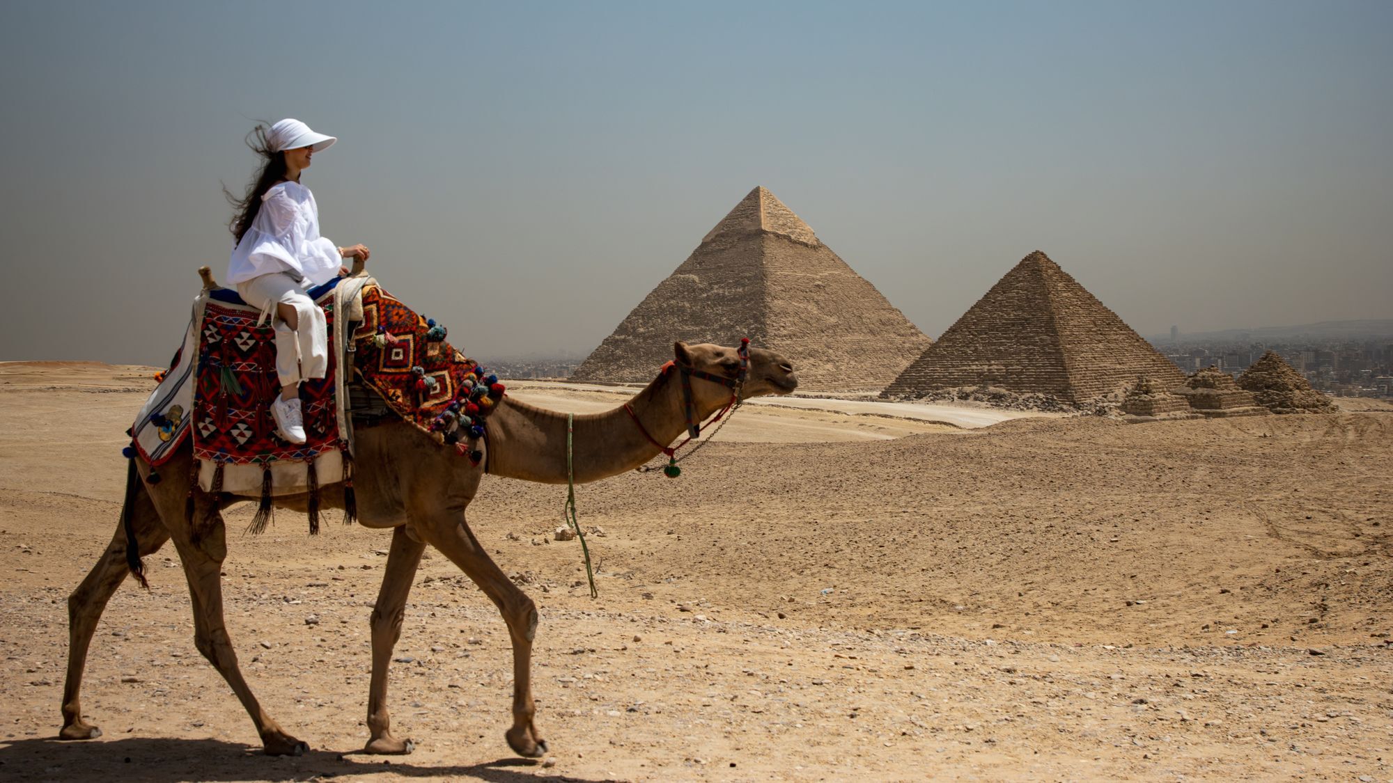 Une cavalière à dos de chameau devant les pyramides